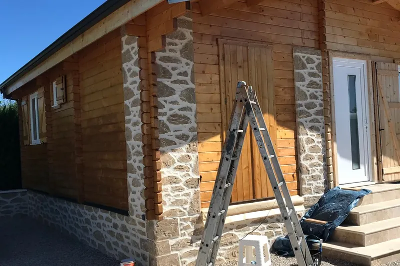 Façade de chalet en bois en cours de lasure, escabeau en place