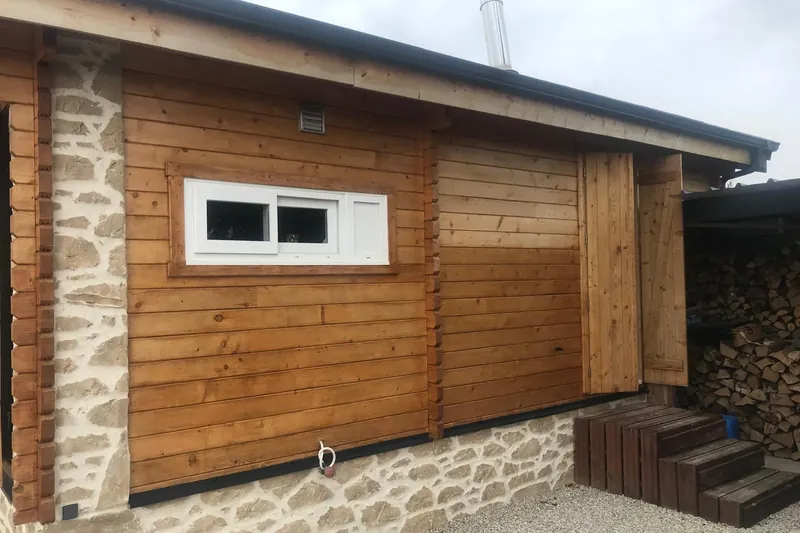 Chalet en madriers de bois lasuré sur soubassement en pierre
