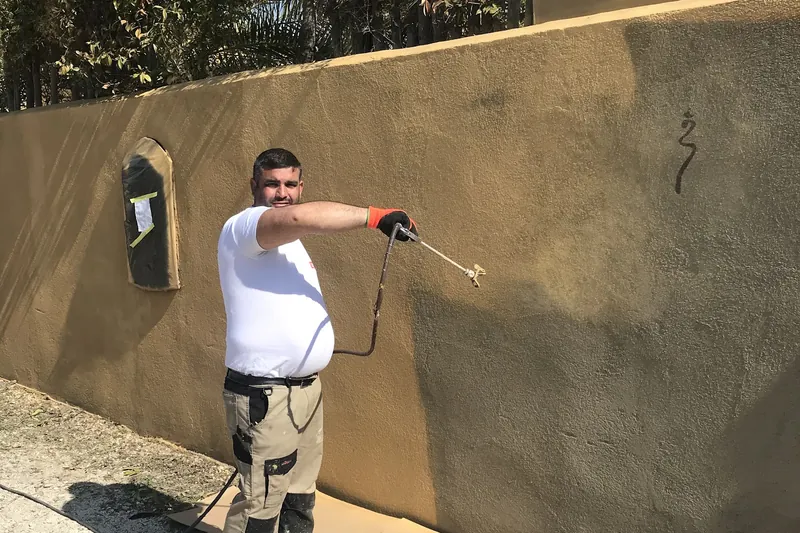 Mise en peinture d'un mur de façade en crépi par pulvérisation, chantier SJ Rénovation