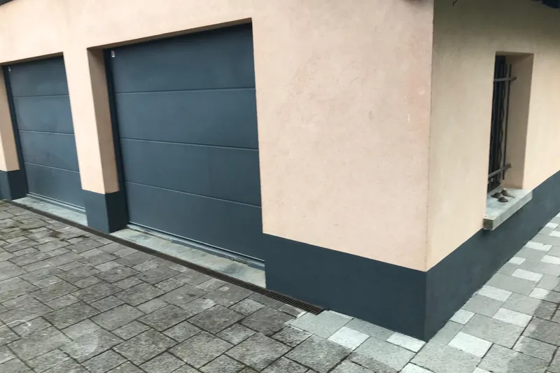 Façade rose poudré avec soubassement repeint en anthracite, portes de garage