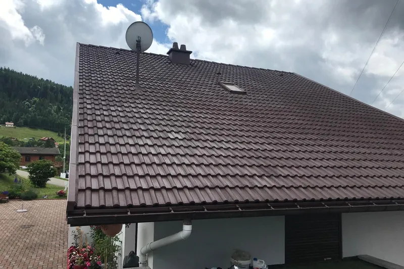 Toiture en tuiles brunes après rénovation, maison au bardage clair